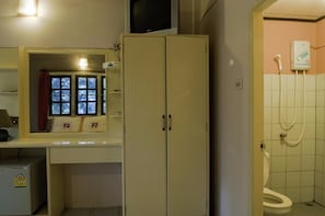 Un baño con inodoro, ducha, un mueble y televisor montado sobre el mueble.