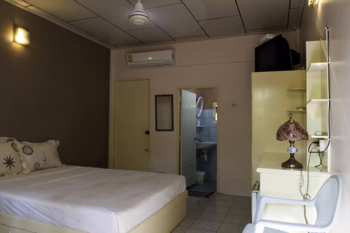 Ein Hotelzimmer mit Bett, Schreibtisch mit Lampe, Spiegel und Klimaanlage.