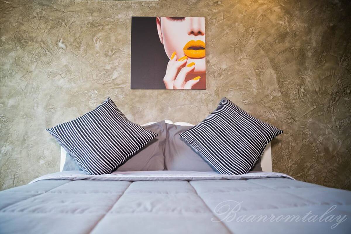 A bed with striped pillows and a framed picture on the wall.
