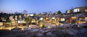 A modern resort with multiple cabins, a rocky landscape, and outdoor lighting. - Nhapha Khao Yai Resort (Pak Chong)