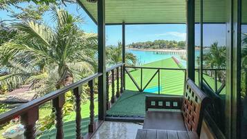 A wooden balcony with a view of a beach and a golf course.