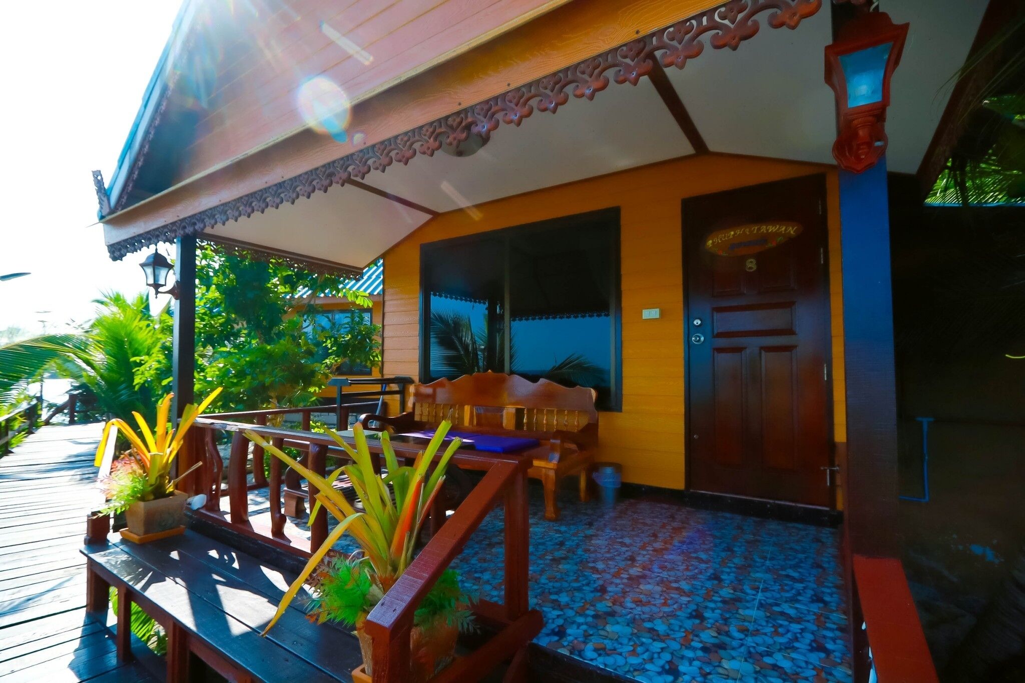 A wooden deck with a bench and potted plants, a wooden door, and a tiled floor.