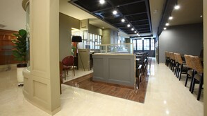A modern interior with a reception desk, seating area, and a large window providing natural light. - Hotel Sopra (Incheon)