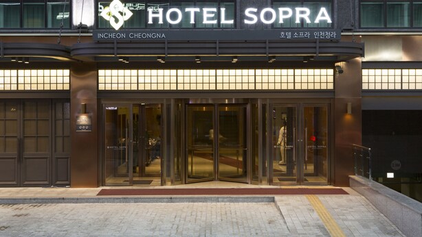 Der Eingang des Hotel Sopra mit einer modernen Glasfassade und Beschilderung in Englisch und Koreanisch.