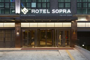 L’entrée de l’hôtel Sopra se distingue par sa façade moderne en verre et son enseigne bilingue, en anglais et en coréen.