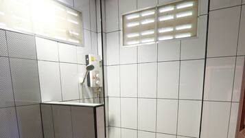 A bathroom with a toilet, a shower area, and a sink.