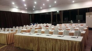 A conference room with rows of tables, each with a white tablecloth and a white chair. - Tubtim Resort (Rayong)
