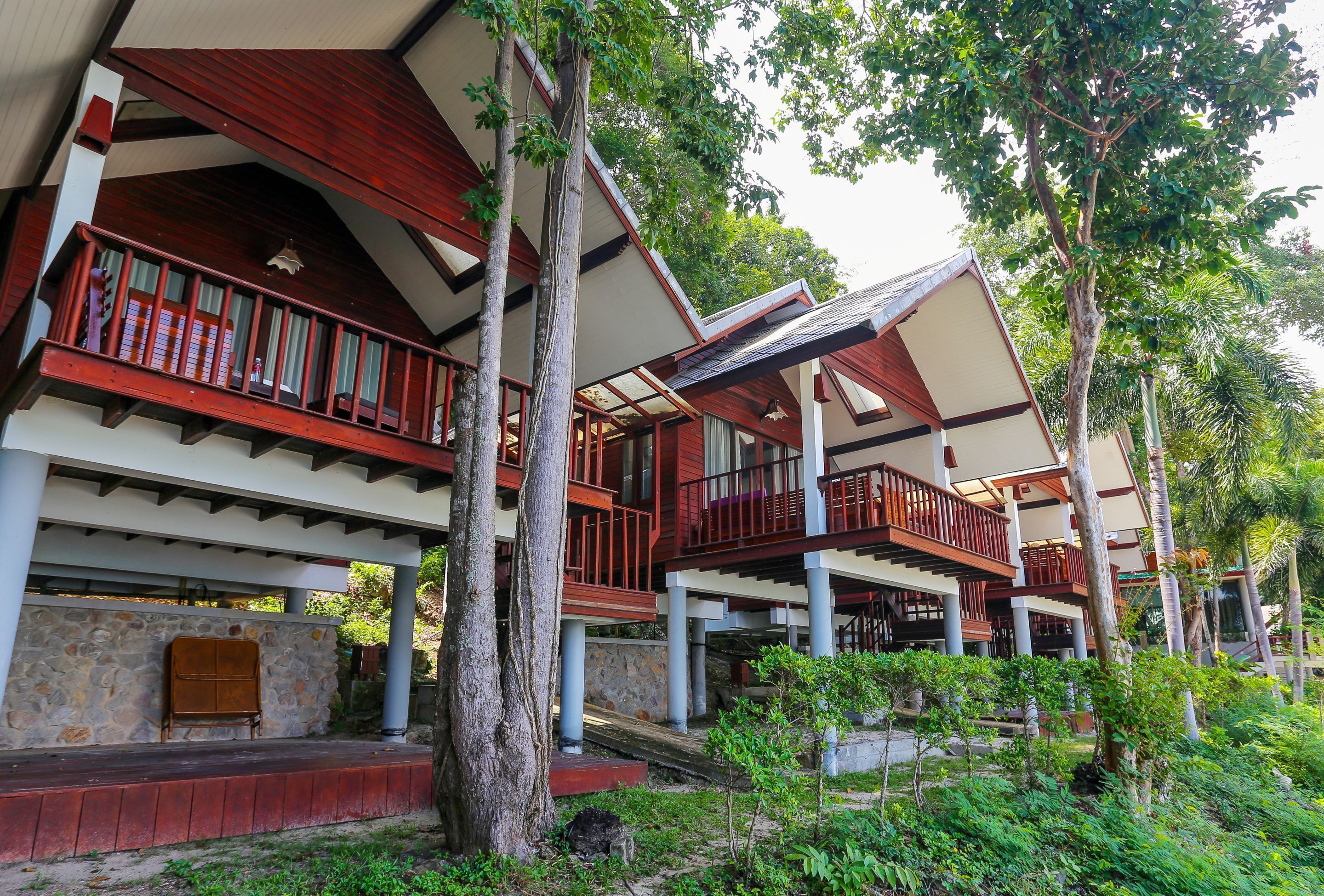 A multi-story building with wooden balconies, stone walls, and a lush garden.