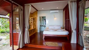 A room with a bed, wooden flooring, and curtains. - Tubtim Resort (Rayong)