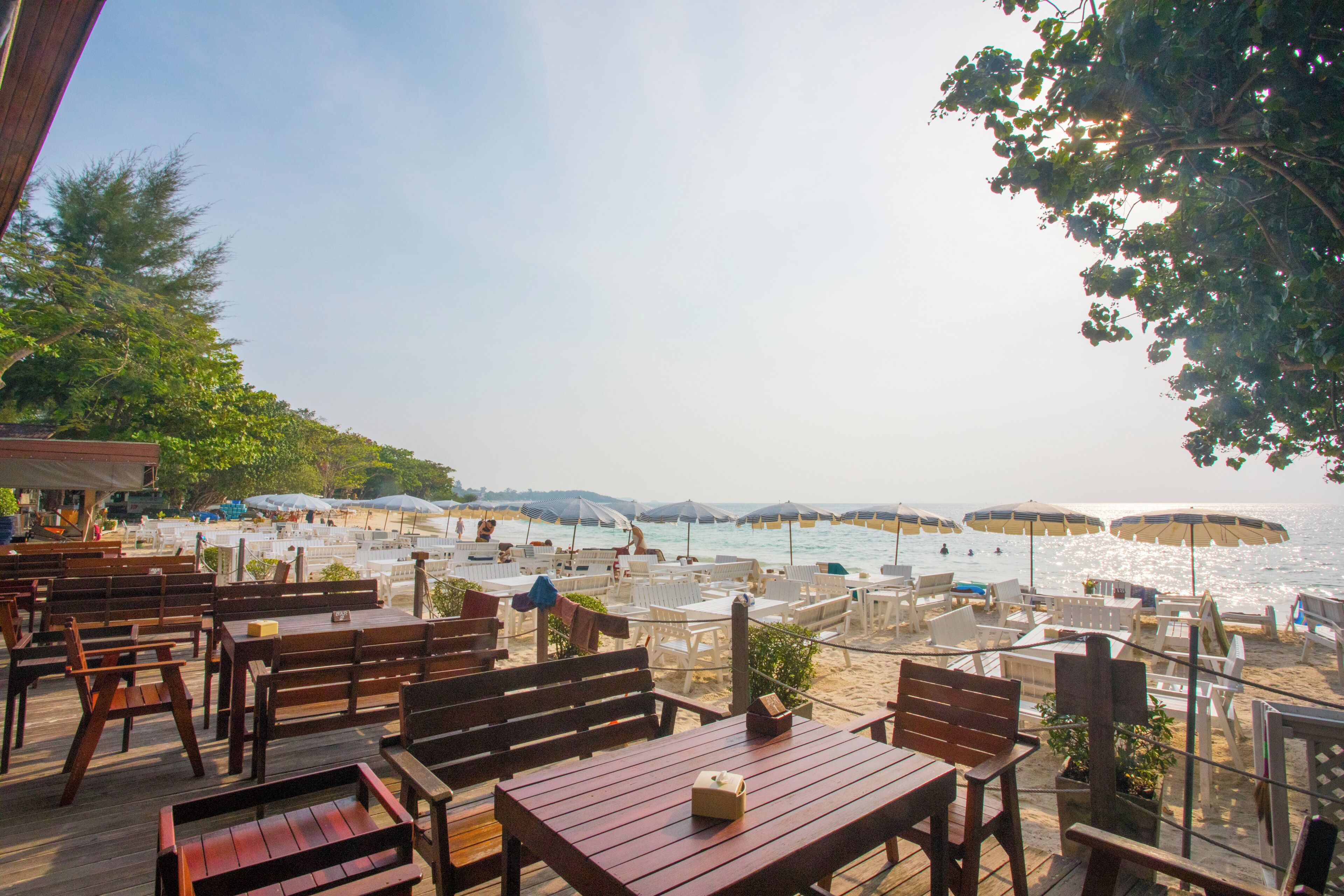 An outdoor seating area with tables and chairs overlooking a beach.