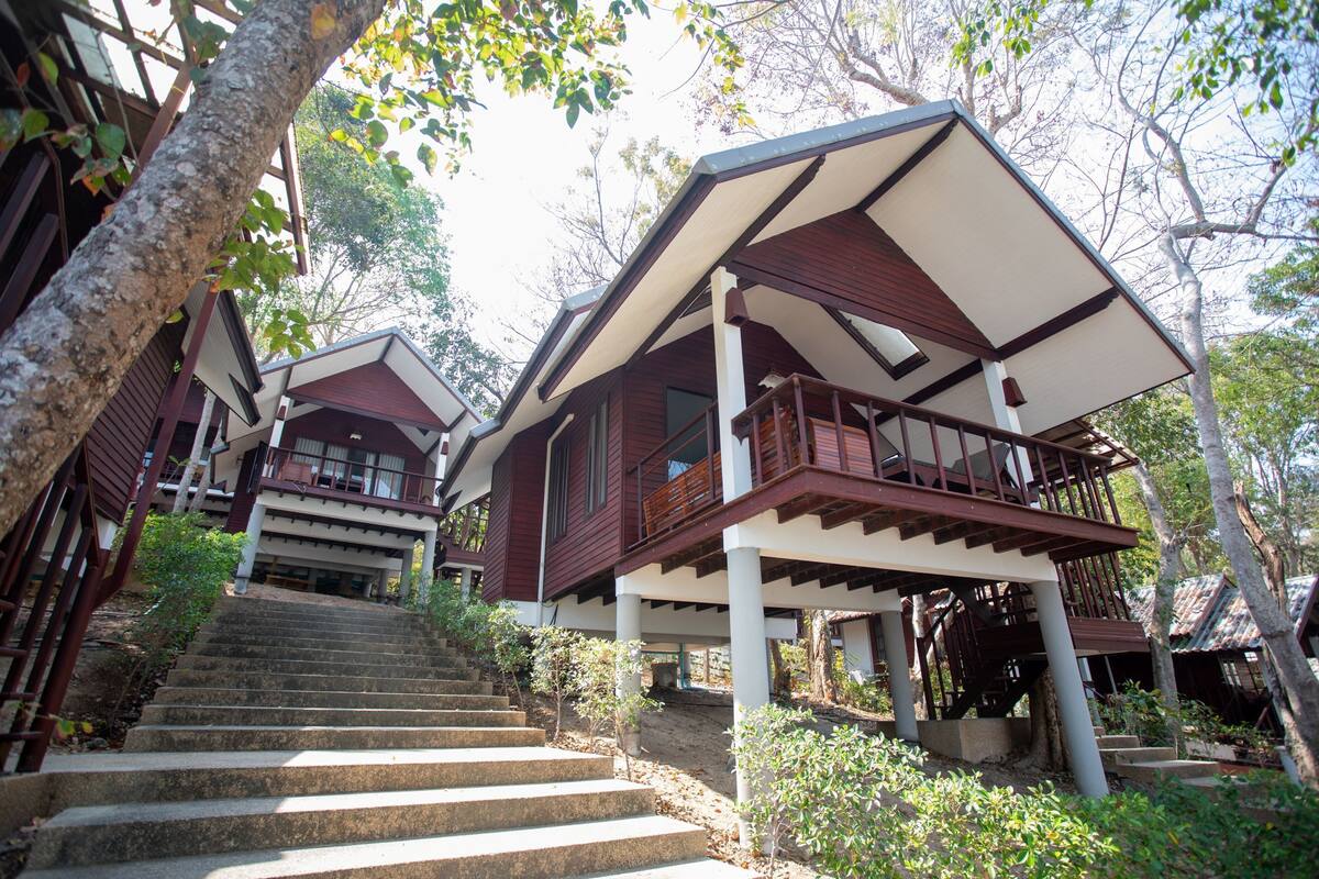 A multi-level wooden house with a staircase leading to a balcony.