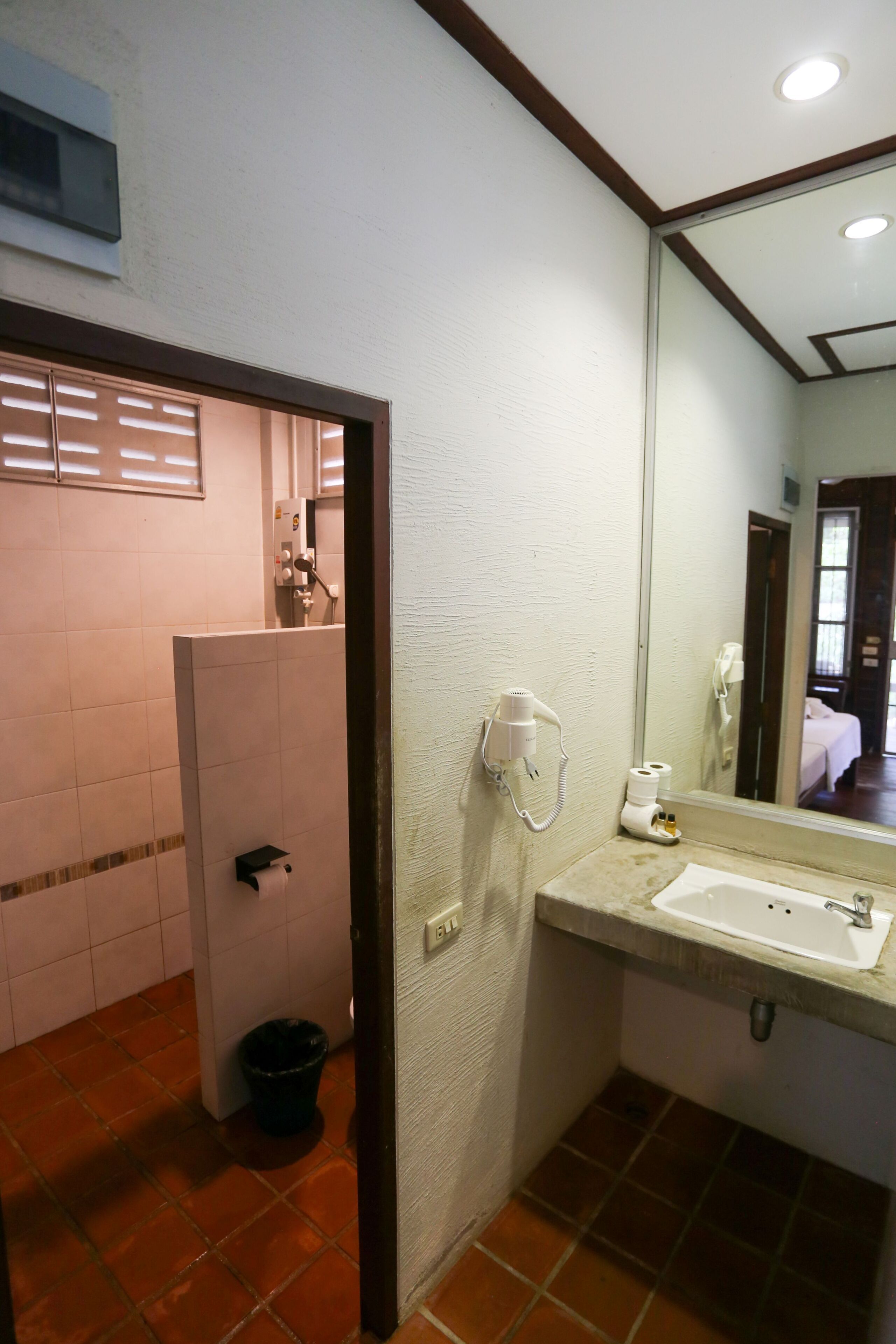 Un baño con lavamanos blanco, un espejo y zona de ducha.