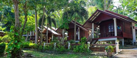 A row of wooden cabins surrounded by lush greenery and trees.