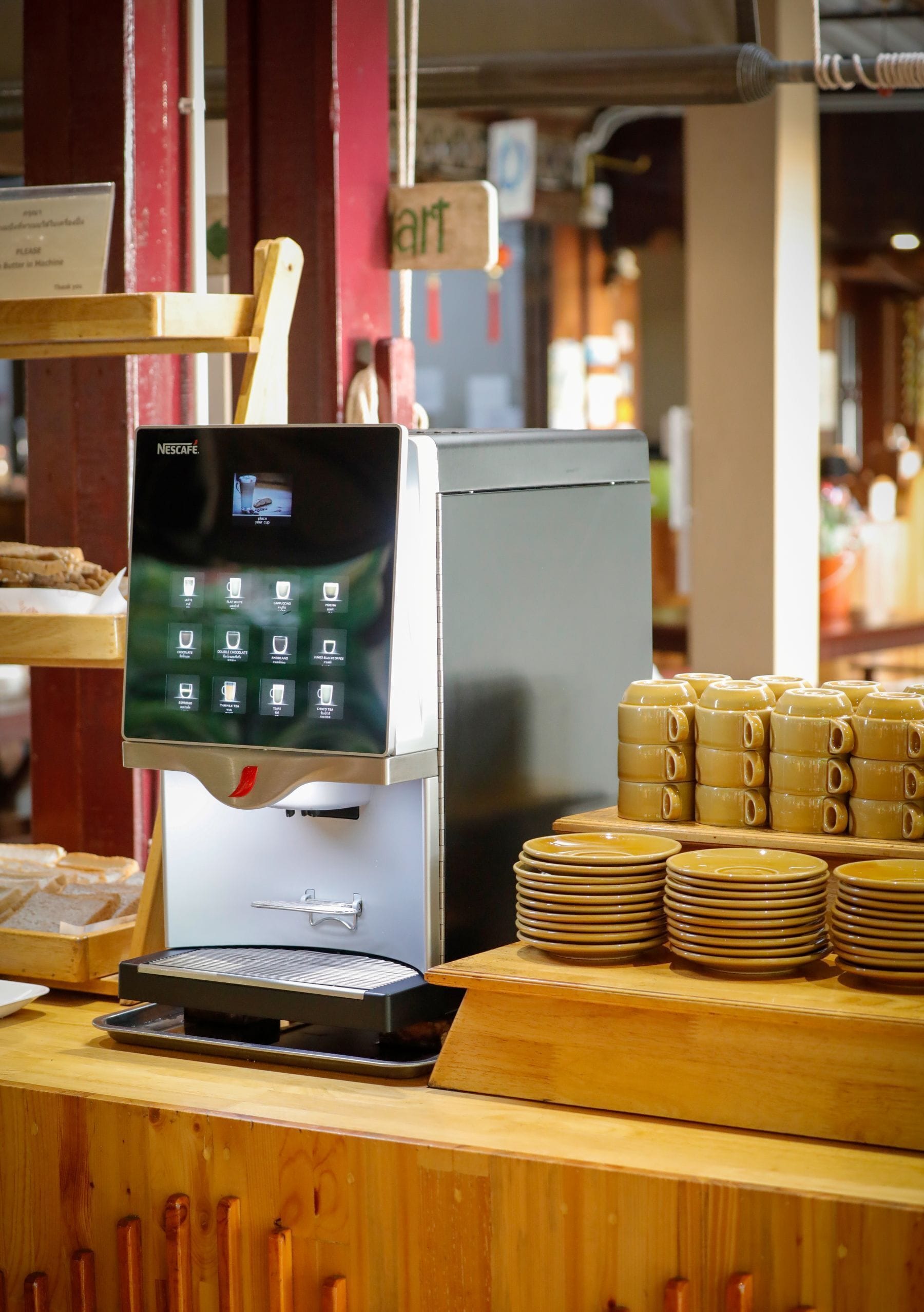 Una cafetera con pantalla digital, platos apilados y un letrero que dice 'ART'.