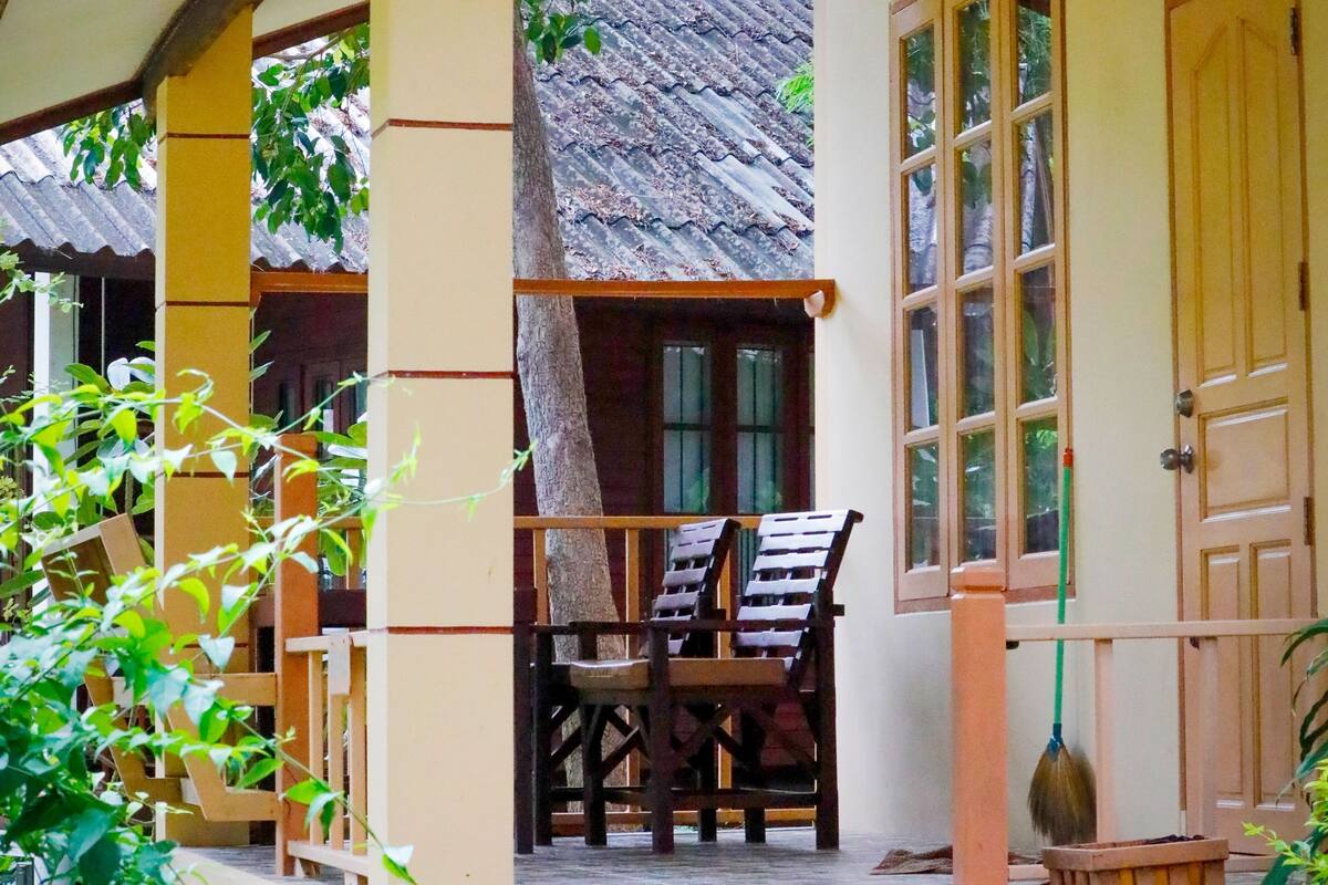 A traditional house with a porch, wooden chairs, and a door.