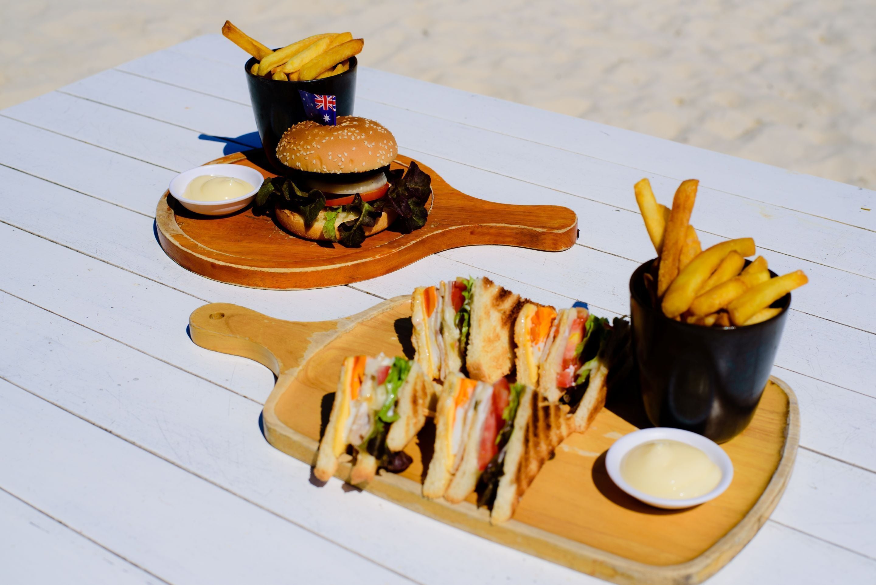 Una mesa de madera con un sándwich y papas fritas sobre una mesa blanca de madera.