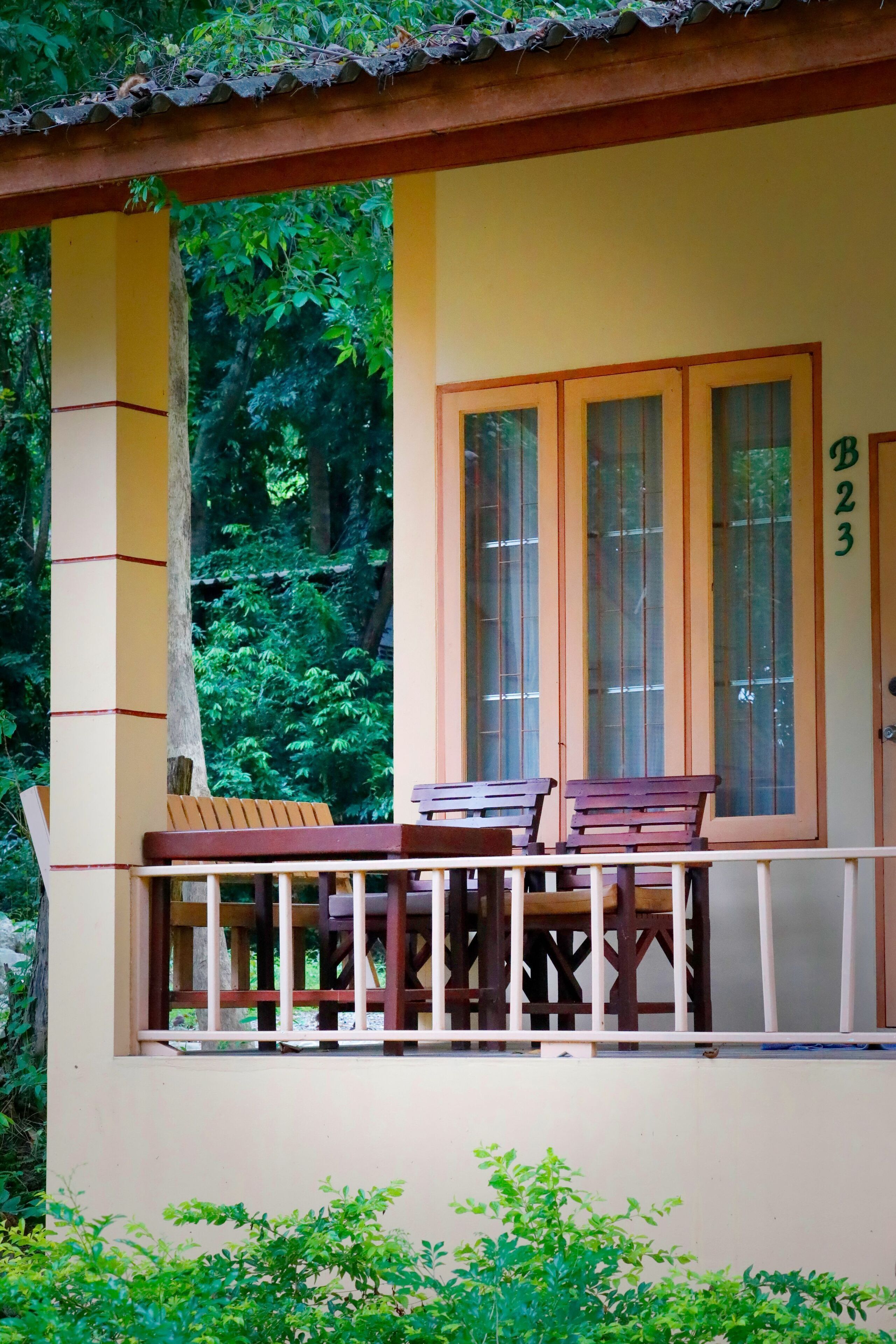 A building with a balcony, wooden benches, and a door marked with the number 23.