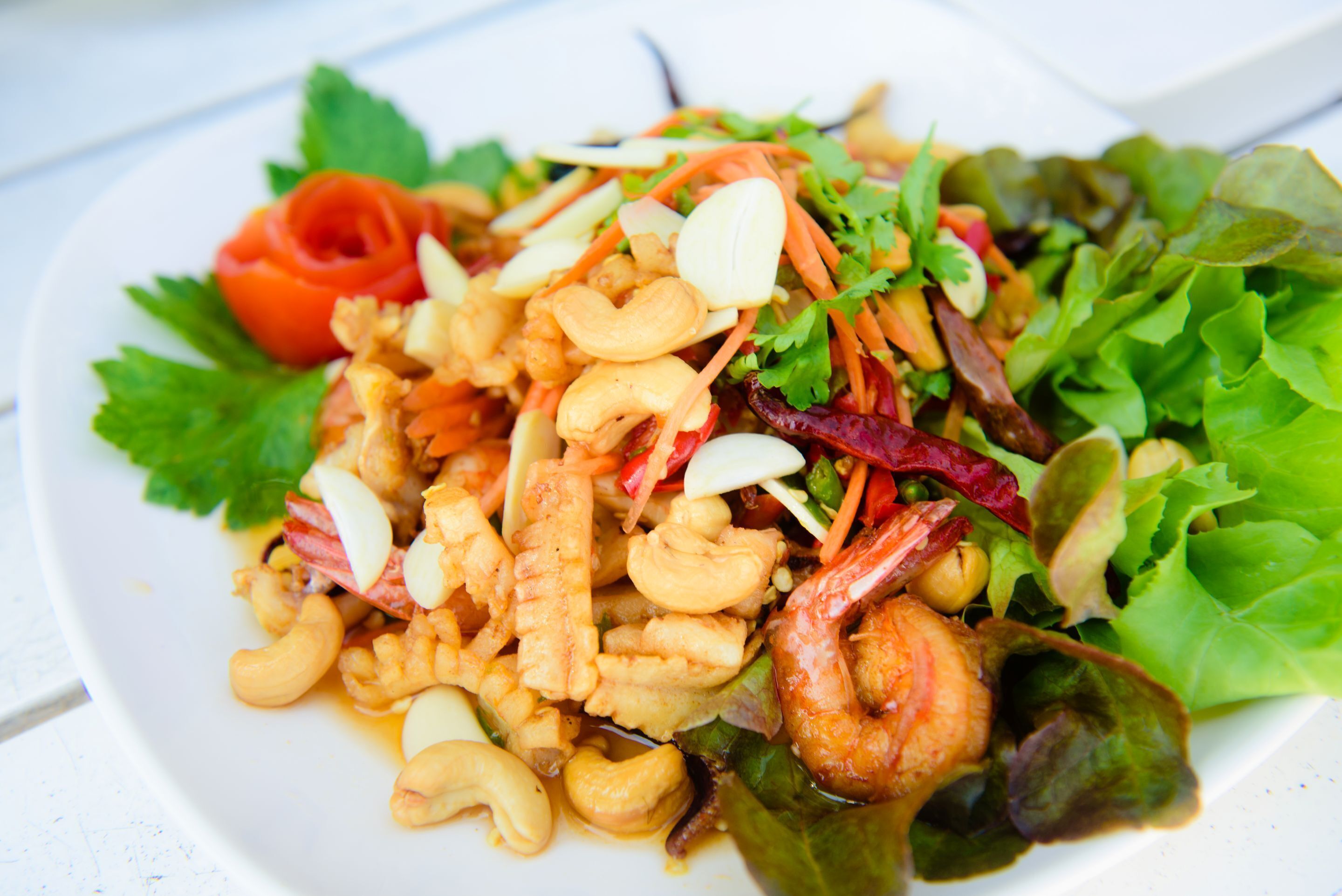 Un plato de comida con camarones, nueces de anacardo y vegetales.