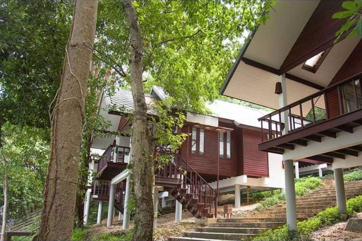 A multi-story house with a wooden exterior, a staircase leading to the upper floor, and a balcony.