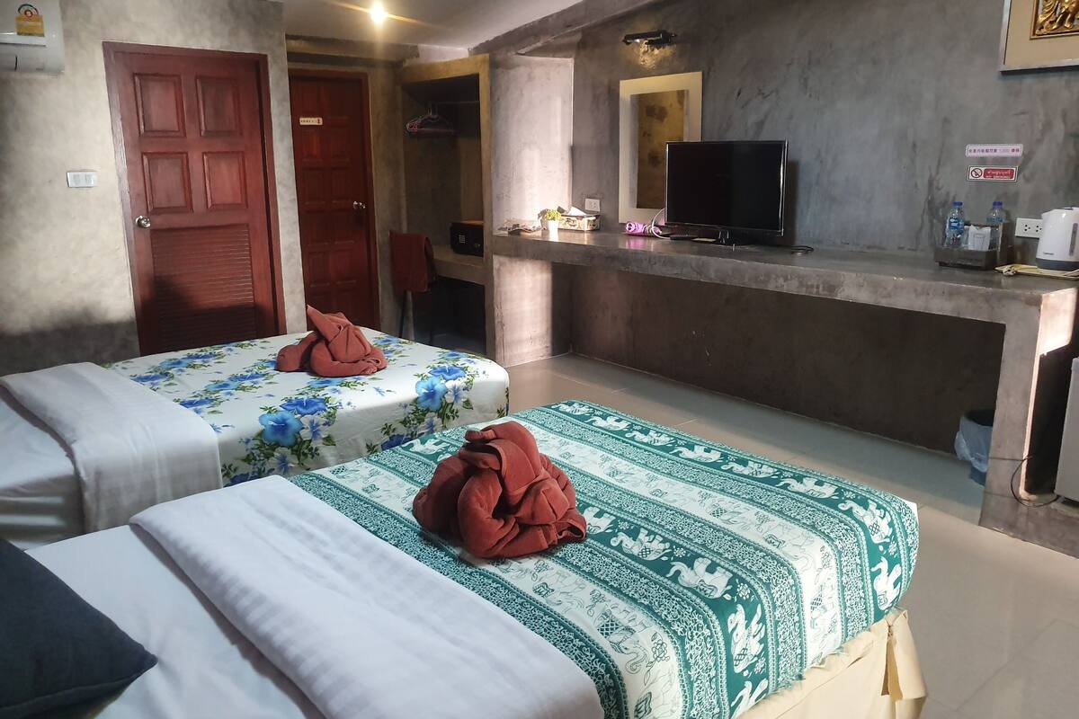 A hotel room with two beds, a TV, and a minibar.