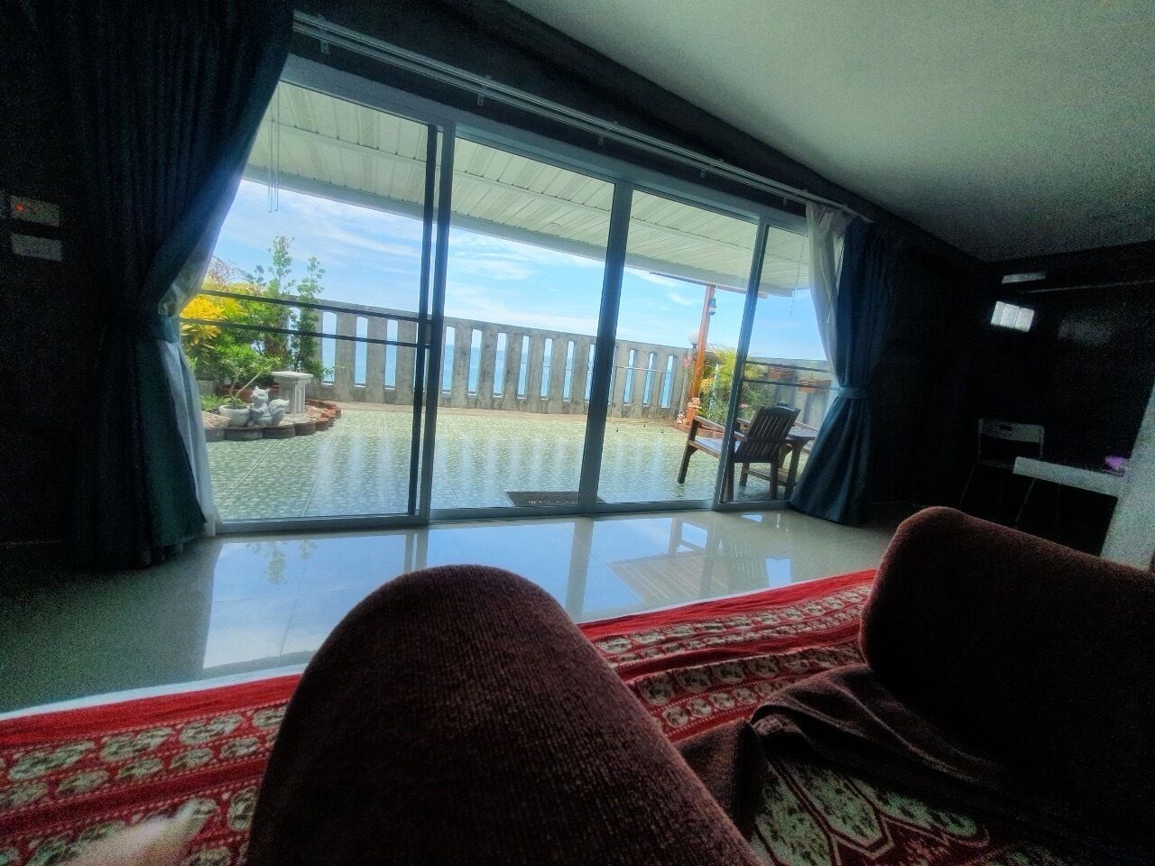 A room with a large sliding glass door leading to an outdoor area with a wooden deck and a view of the sky.