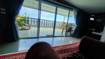 A room with a large sliding glass door leading to an outdoor area with a wooden deck and a view of the sky.