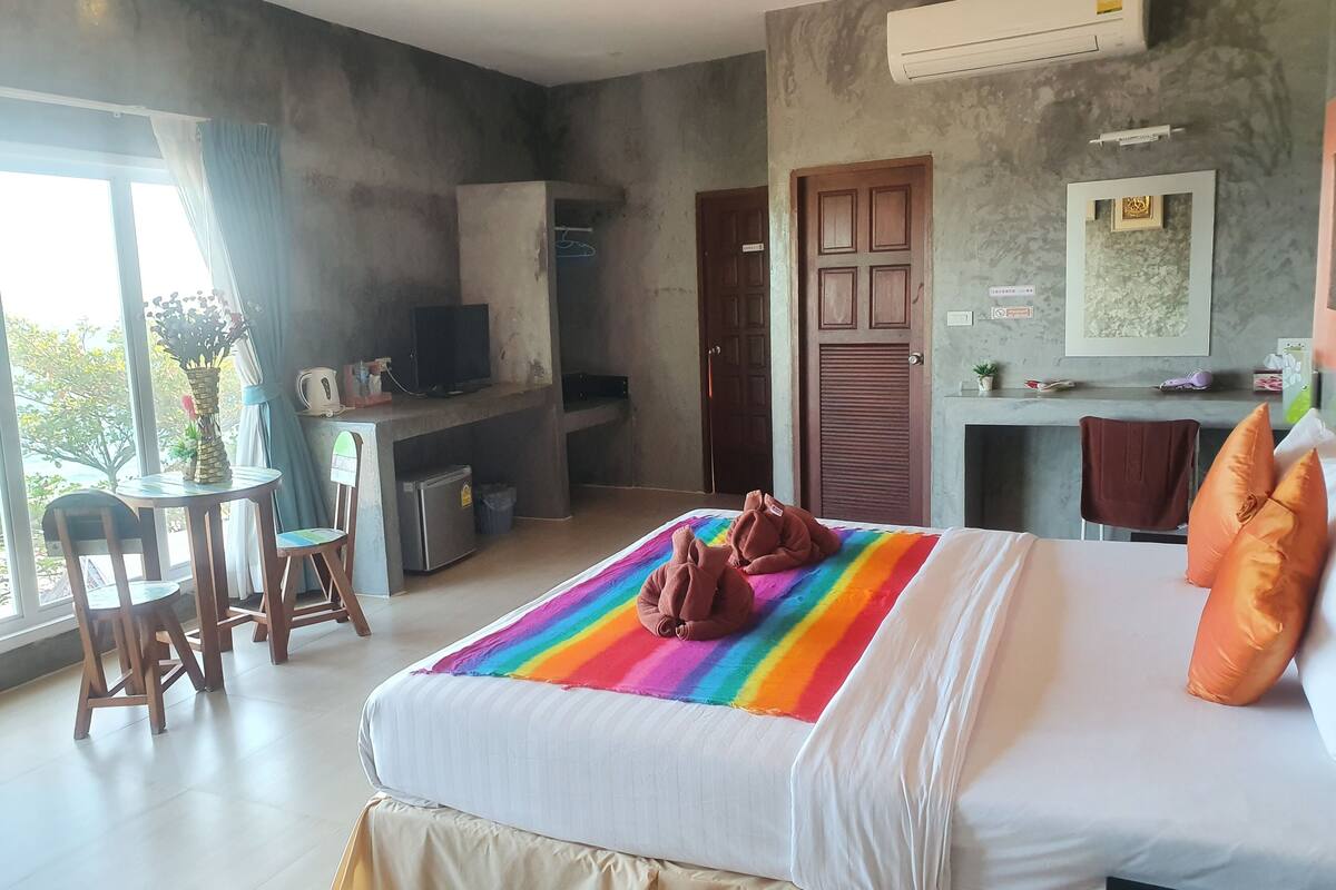 A hotel room with a bed, a desk, a chair, a TV, and a window.