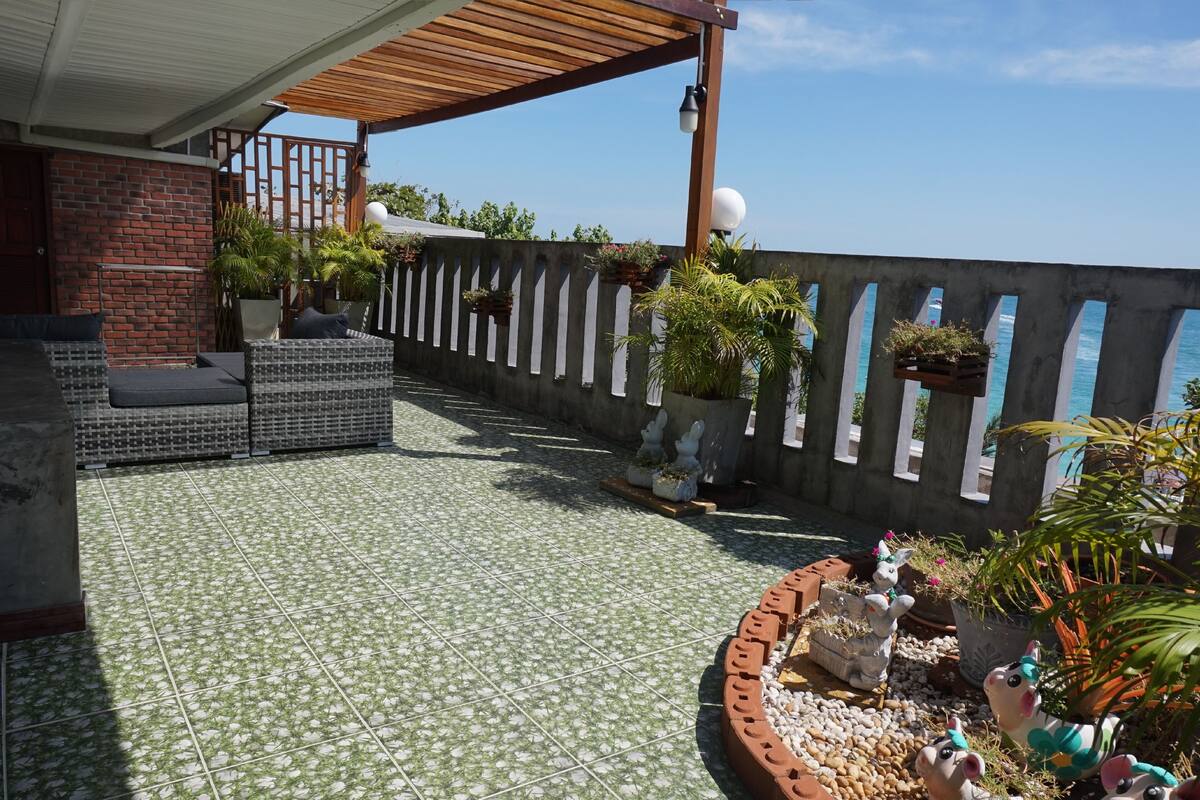 A rooftop patio with tiled flooring, outdoor furniture, potted plants, and decorative animal figurines.