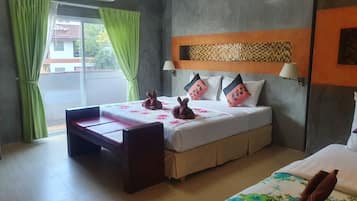 A hotel room with a bed, a small table, a window with curtains, and an air conditioning unit.