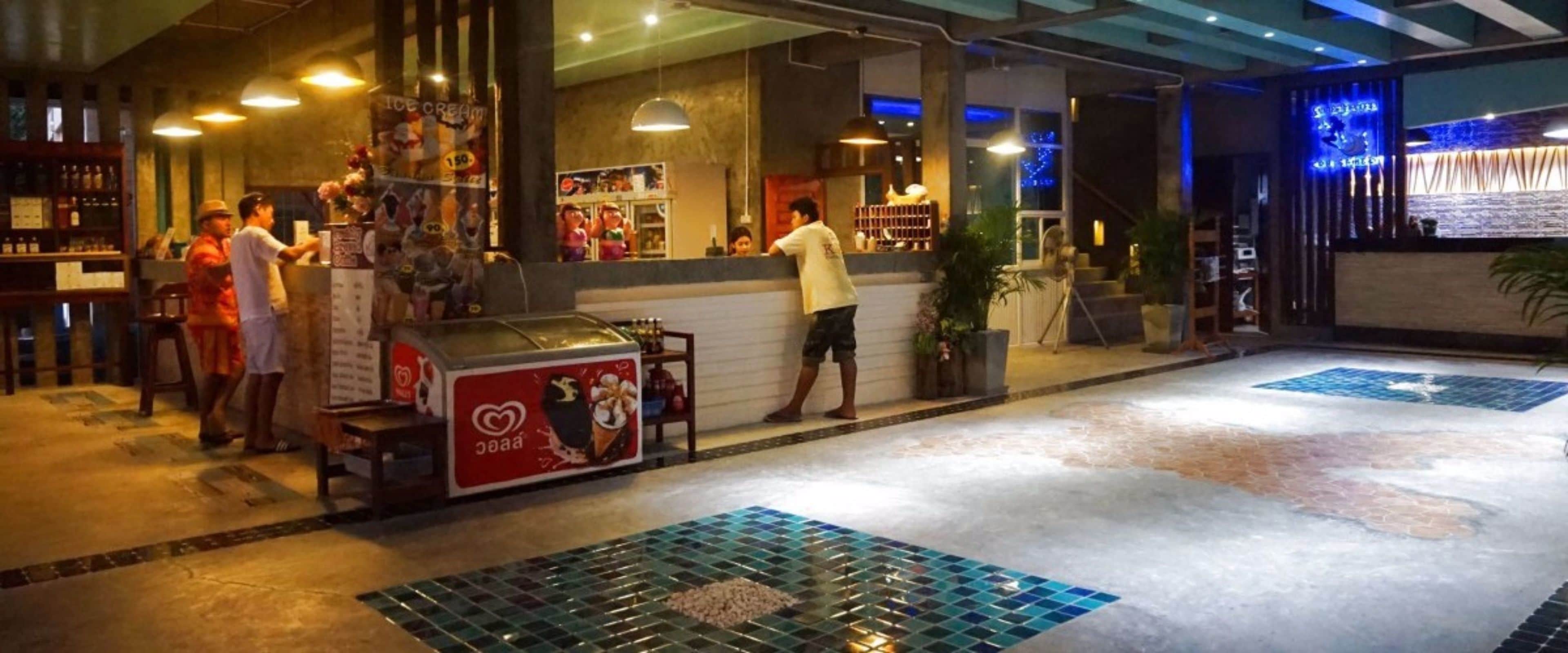A restaurant with a counter, a menu stand, and a seating area with a tiled floor.