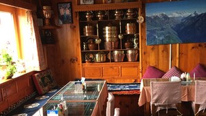 Un intérieur en bois comprenant un coin repas, une collection de poteries et un tableau représentant une vue sur la montagne.