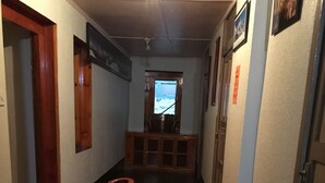 Un couloir étroit avec un plancher en bois, une rambarde en bois et une fenêtre au bout.