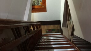 Un escalier avec des rampes en bois menant à un palier d’où l’on peut admirer une montagne et un arc-en-ciel.
