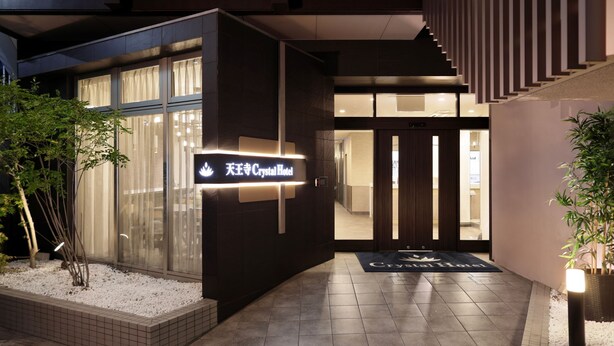 L’extérieur du Crystal Hotel présente un design moderne, avec une enseigne, un escalier et un hall d’entrée bien entretenu agrémenté de plantes.