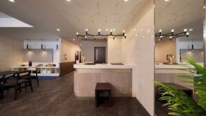 Un hall d’hôtel moderne, doté d’un comptoir d’accueil, d’un espace salon et d’un grand miroir qui reflète l’ensemble de la pièce.