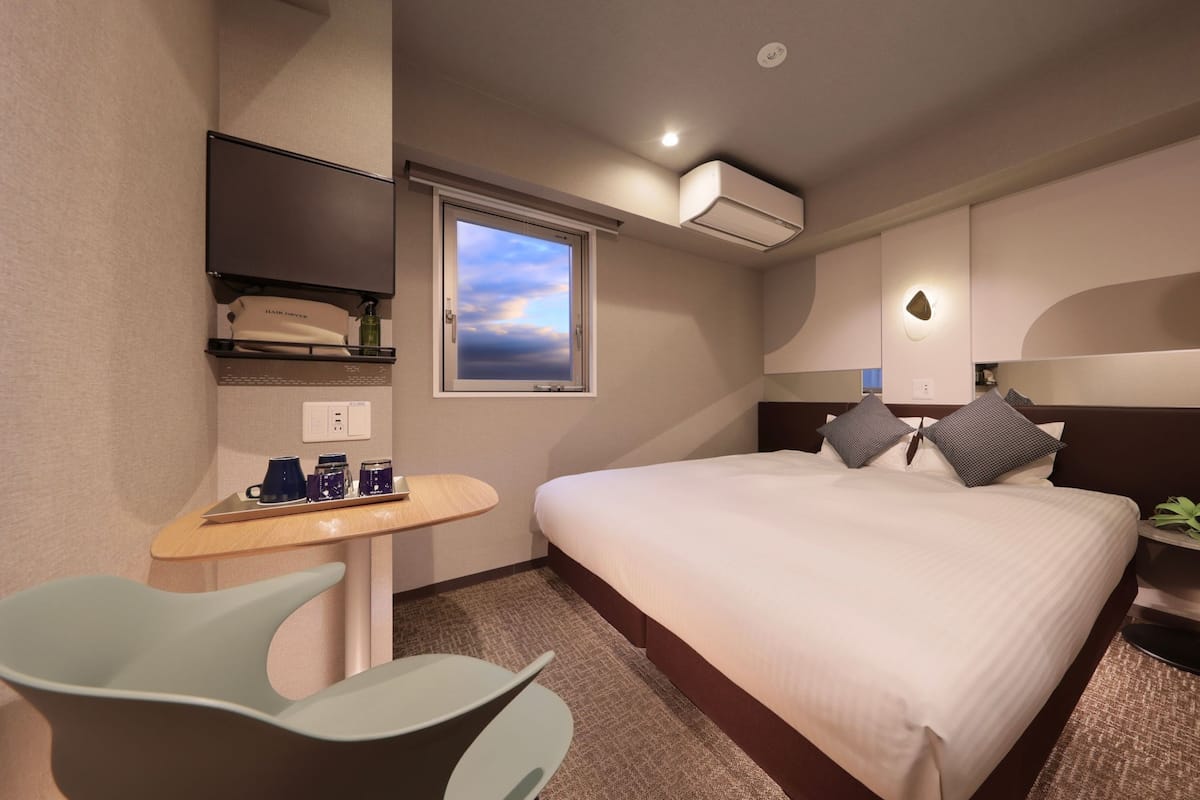 Une chambre d’hôtel avec un lit, un bureau et une chaise, une télévision et une fenêtre donnant sur un beau paysage.