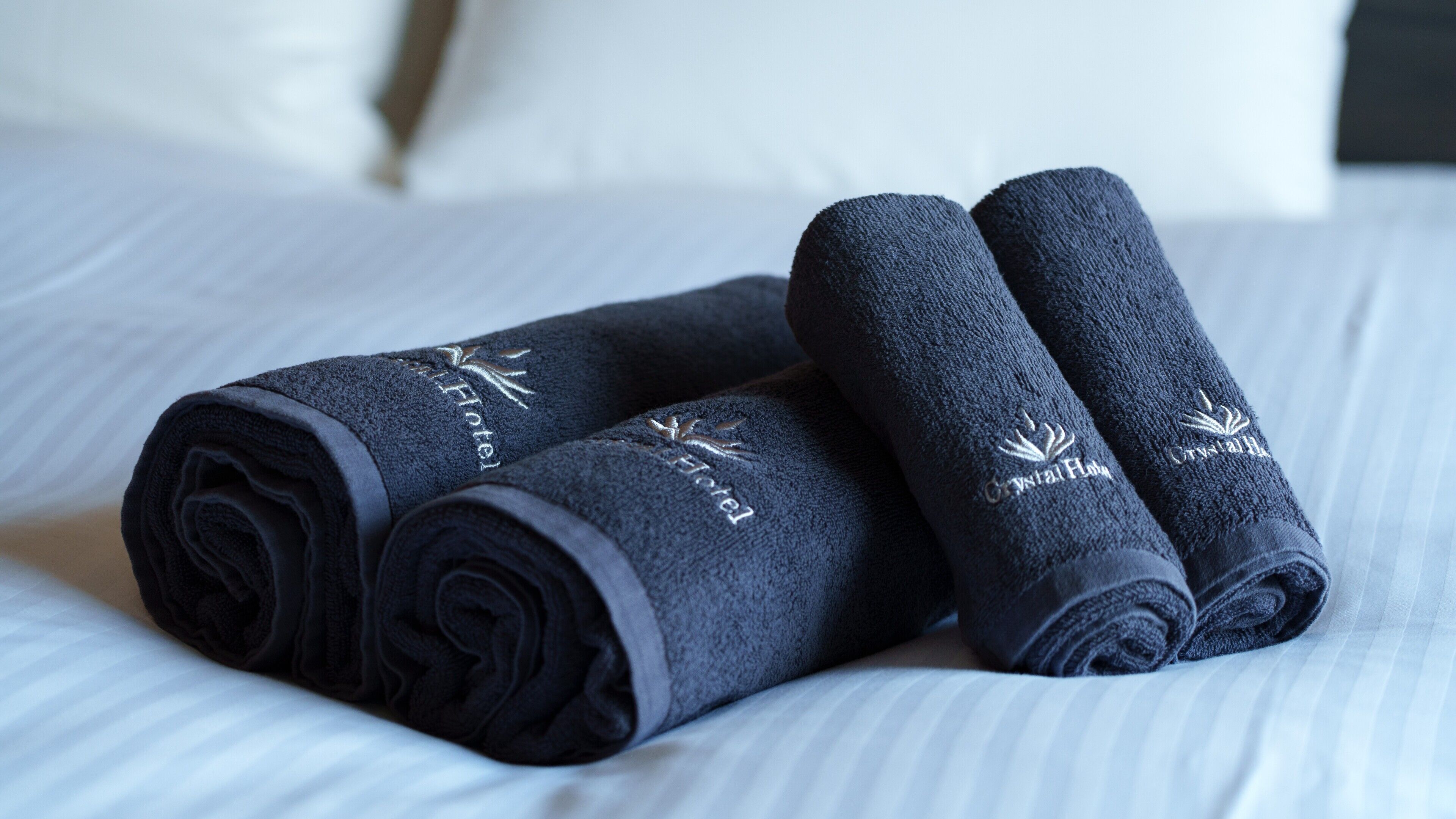 Três toalhas dobradas com logotipos bordados sobre a cama.