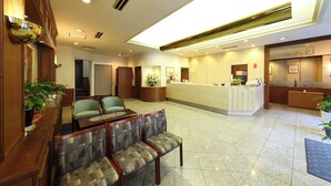 A hotel lobby with a reception desk, seating area, and potted plants. - Nagasaki IK Hotel (Nagasaki)