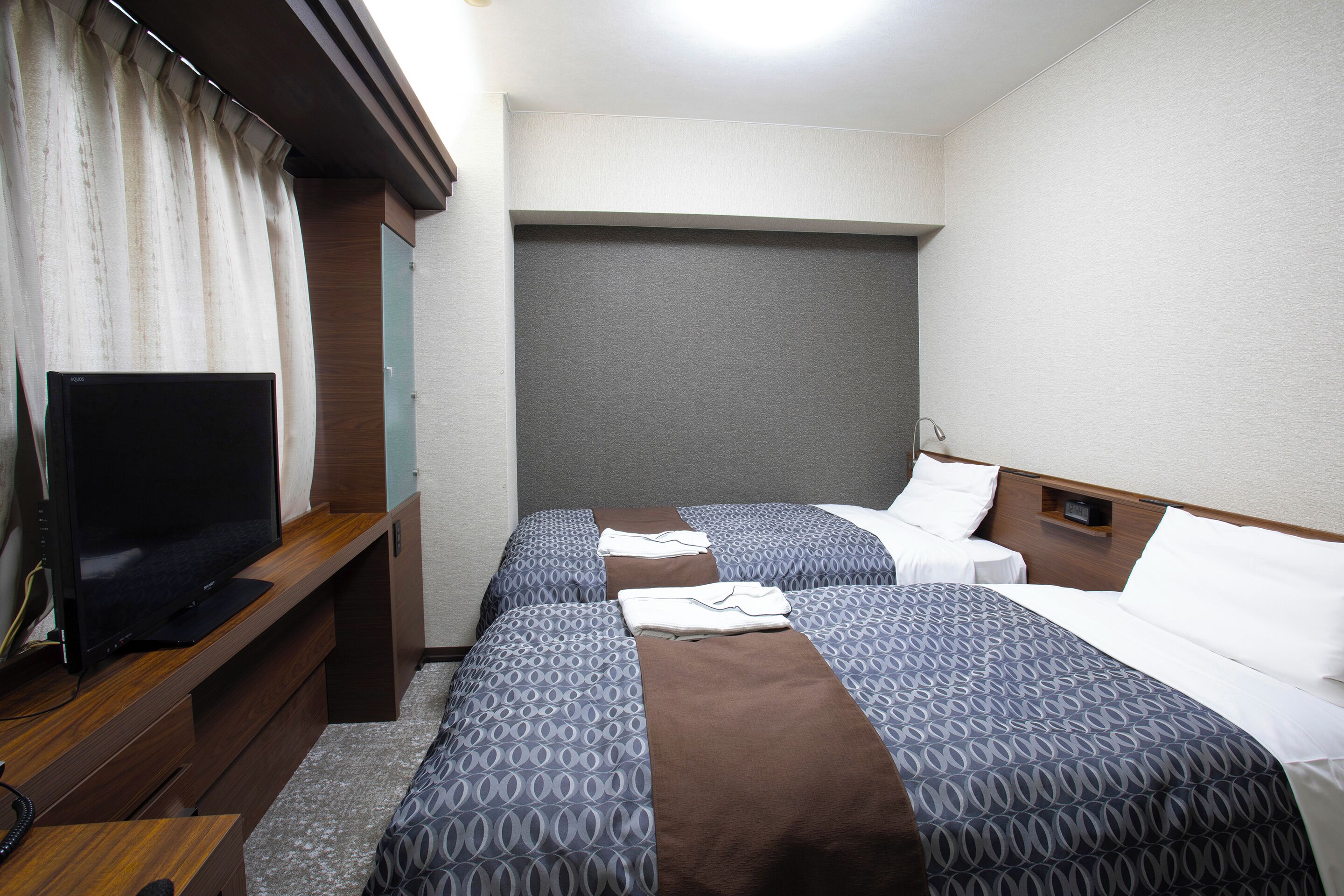 Une chambre d’hôtel avec deux lits, une télévision et un bureau en bois.