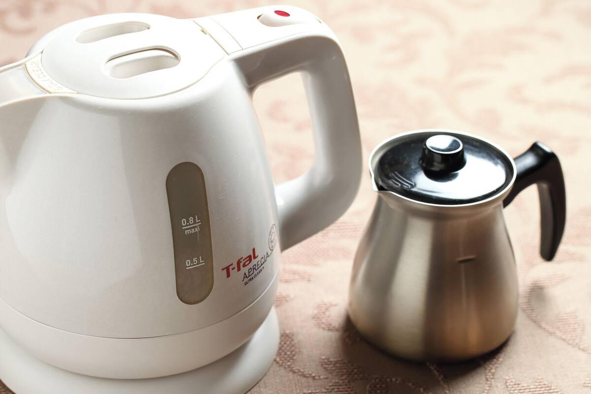 Een witte elektrische waterkoker met handvat en een roestvrijstalen koffiepot.