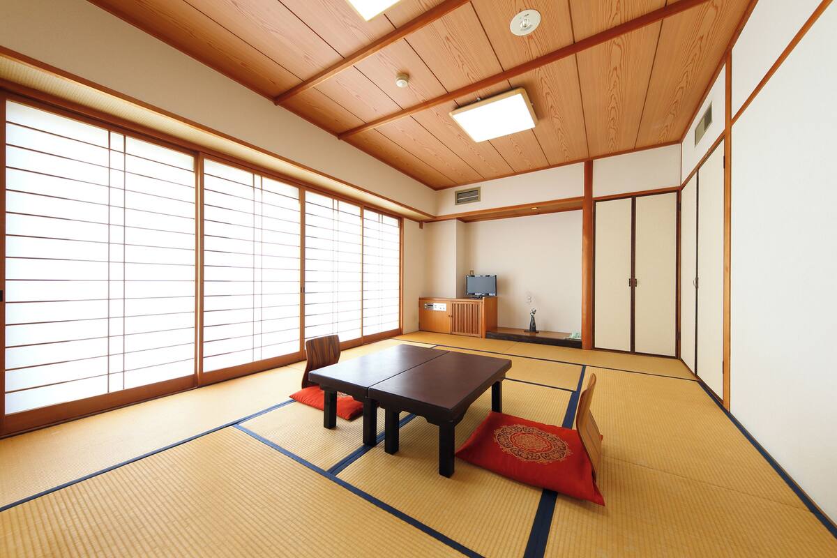 Een traditionele Japanse kamer met tatami vloeren, een lage houten tafel, schuifdeuren en een televisietoestel.