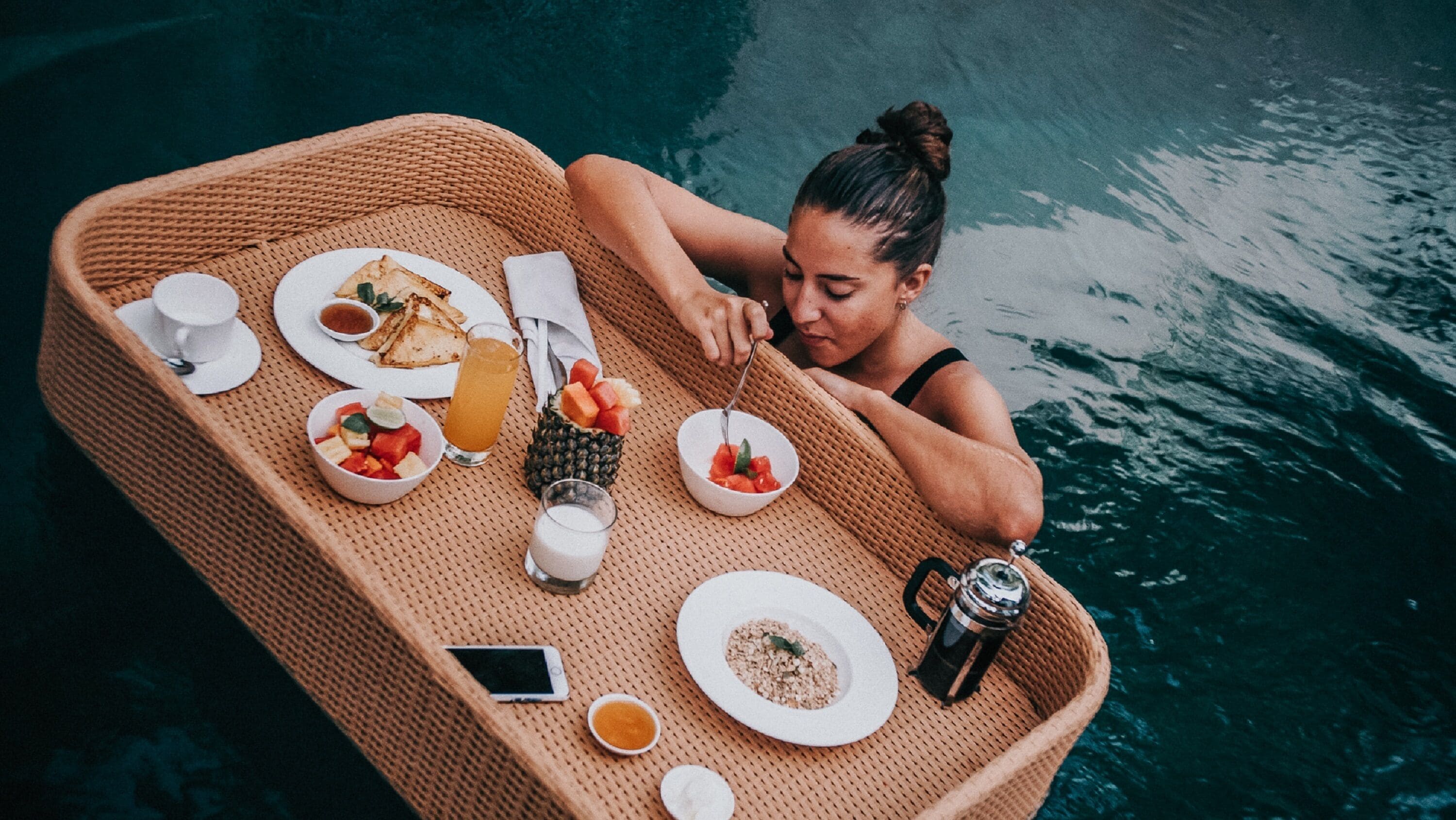 A dining setup on a boat with plates of food, a drink, and a salt shaker.