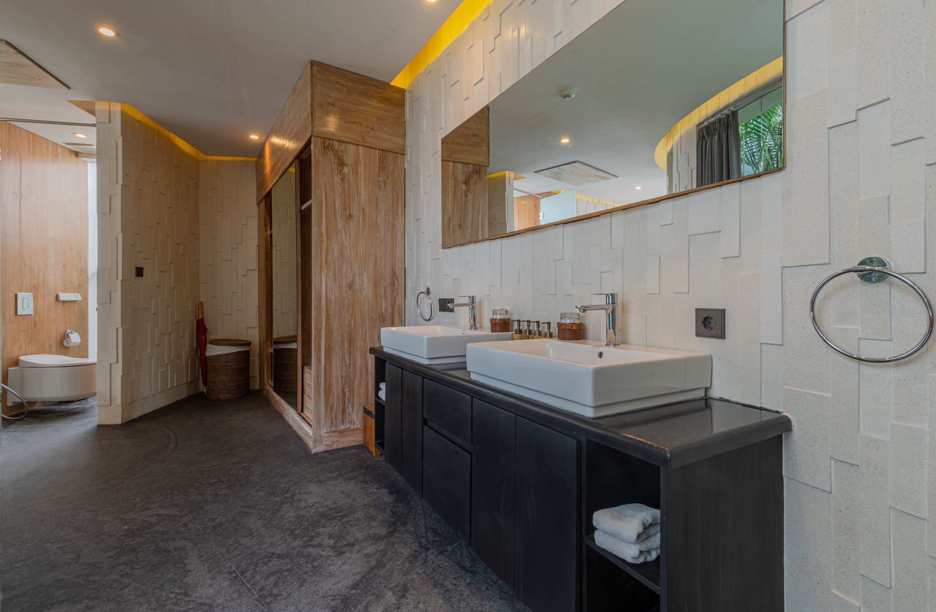 A modern bathroom with two sinks, a large mirror, and a wooden accent wall.