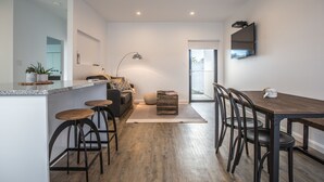 Una cocina moderna con barra, taburetes de madera y una mesa de comedor con sillas.