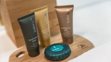 Una tabla de madera con tres productos para el cuidado de la piel y una barra de jabón.