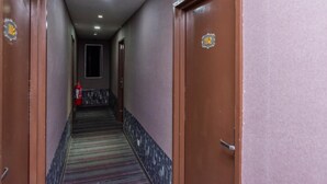 Um corredor com portas em ambos os lados, um extintor de incêndio à esquerda e um tapete estampado.
