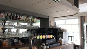 A bar area with shelves of liquor bottles, glasses, and a coffee machine. - Gasterij Berg & Dal (Slenaken)