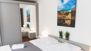 A hotel room with a bed, bedside tables, lamps, and a painting of a landscape. - Gasterij Berg & Dal (Slenaken)
