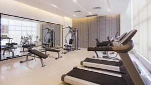 Un gimnasio moderno con cintas de correr, máquinas de pesas y un espejo grande.
