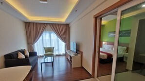 Una habitación de hotel con sofá, una mesa de centro, televisor y cama.